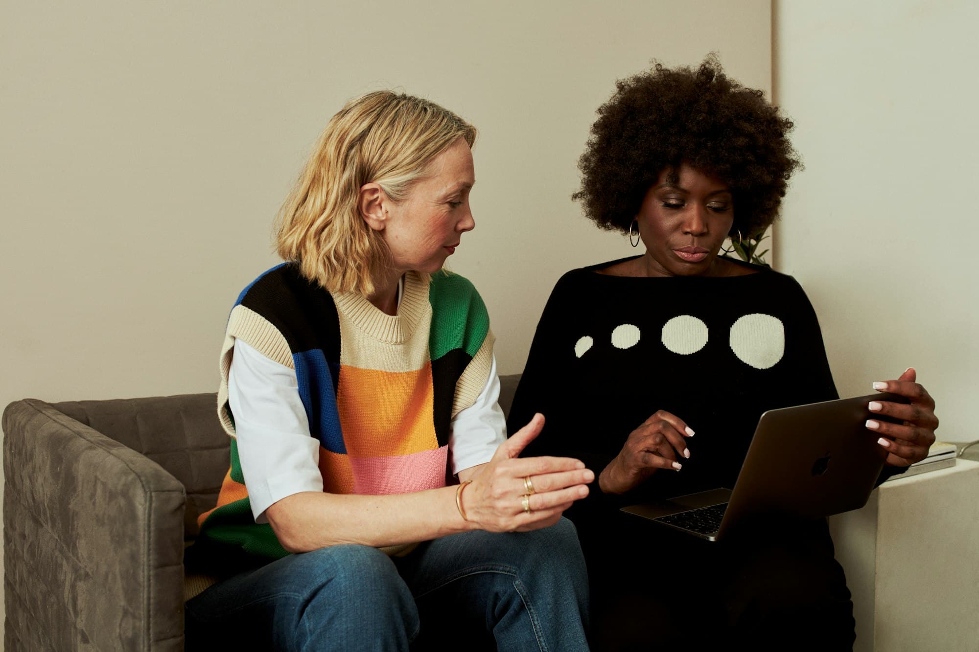 Two business partners sitting in front of a laptop, one pointing at the screen and asking a question