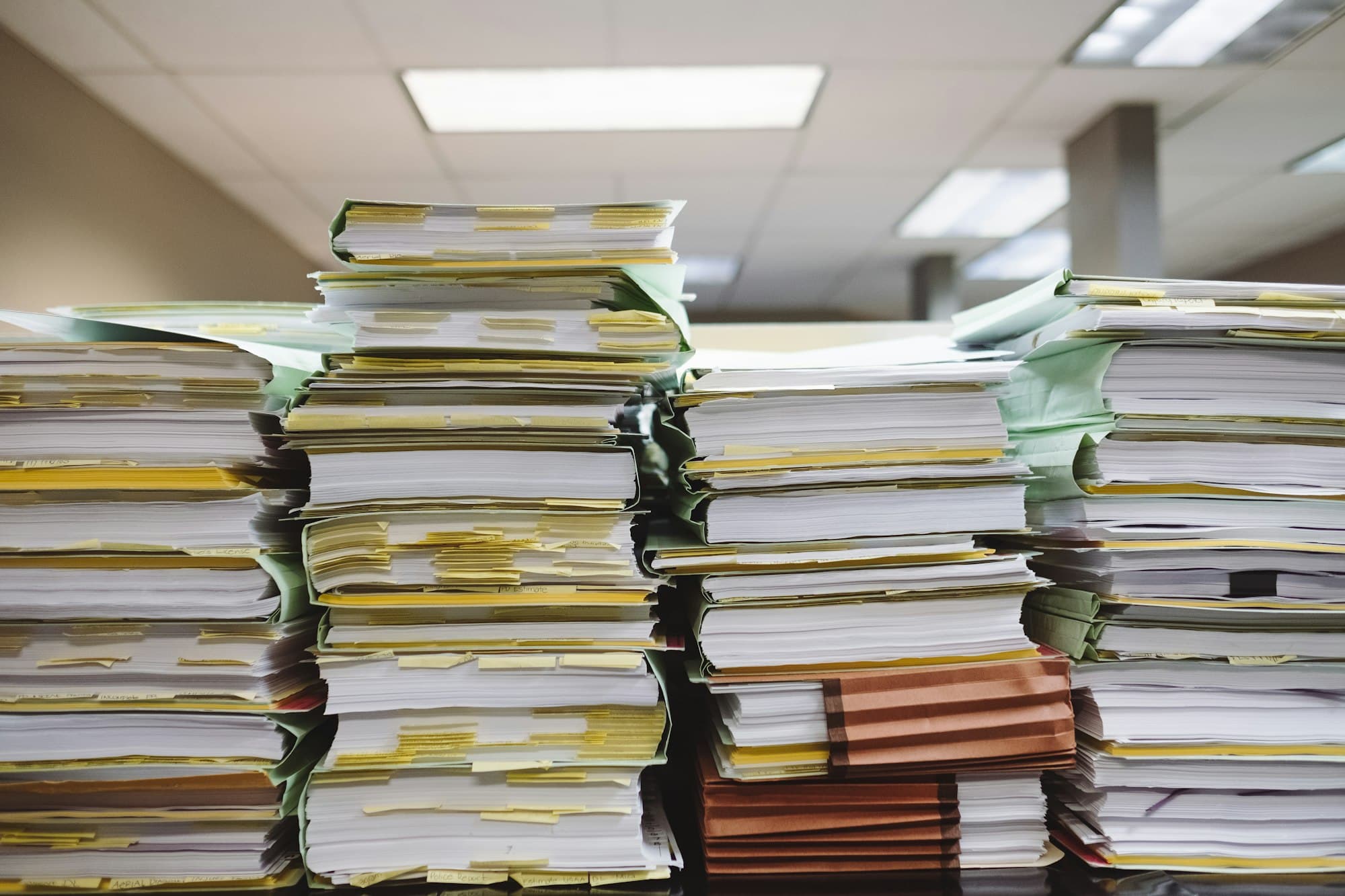 Des piles de dossiers papier empilés sur un bureau