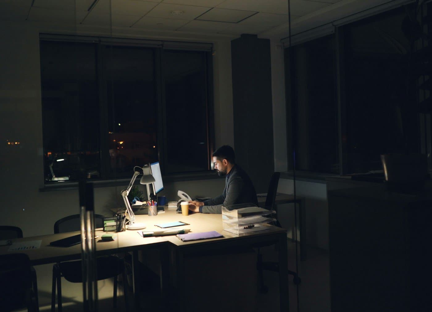A man alone at his desk in the evening, in an empty office where only his screen is on