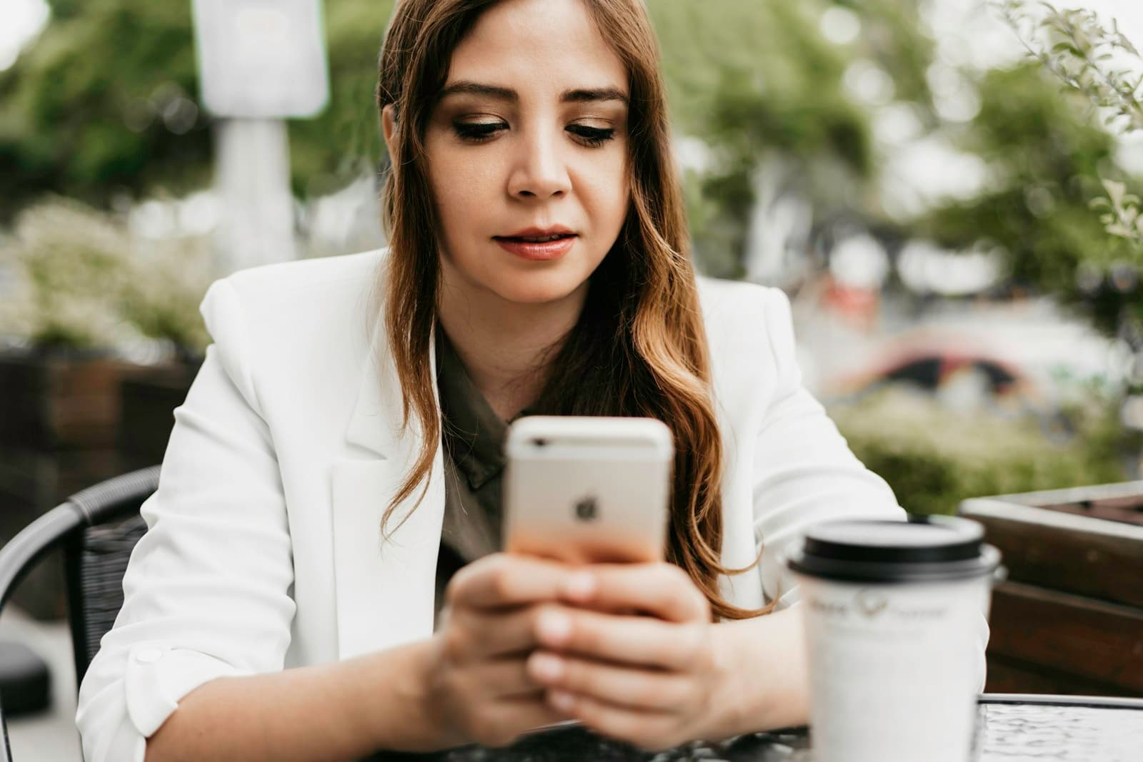A woman in a blazer reading something on her phone, her face closed